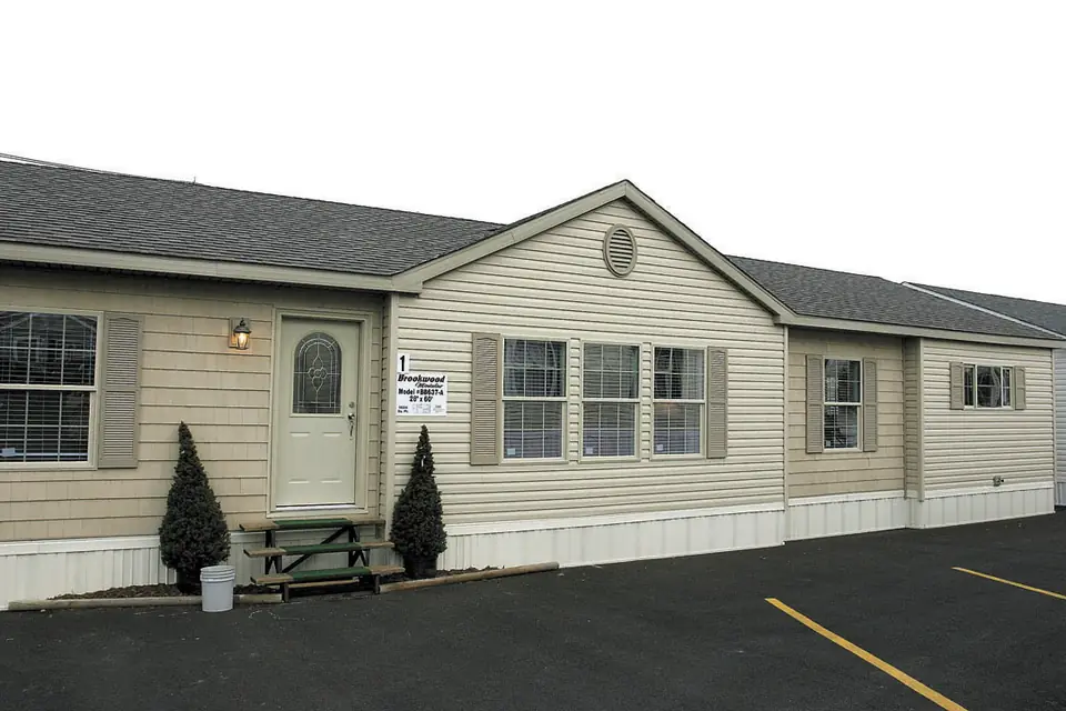 A multi-section manufactured home with vinyl siding and a small front stoop