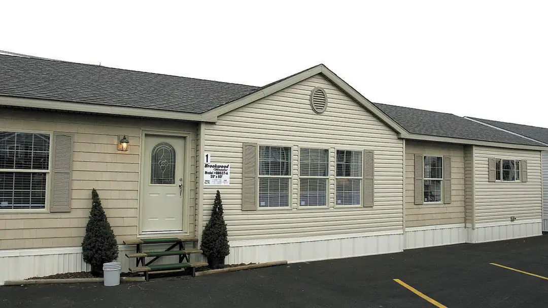 A multi-section manufactured home with vinyl siding and a small front stoop